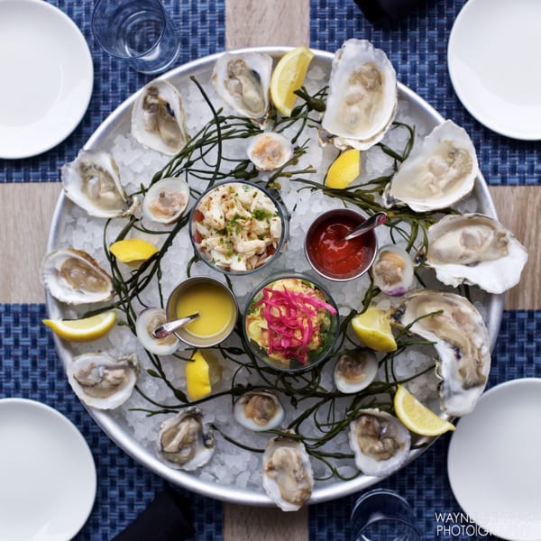 Overhead view of a seafood platter with oysters, clams, crab, and sauces on ice.