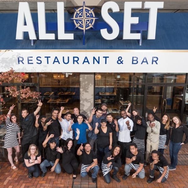 The All Set Restaurant & Bar team, a diverse group of staff, poses happily outside the seafood restaurant.