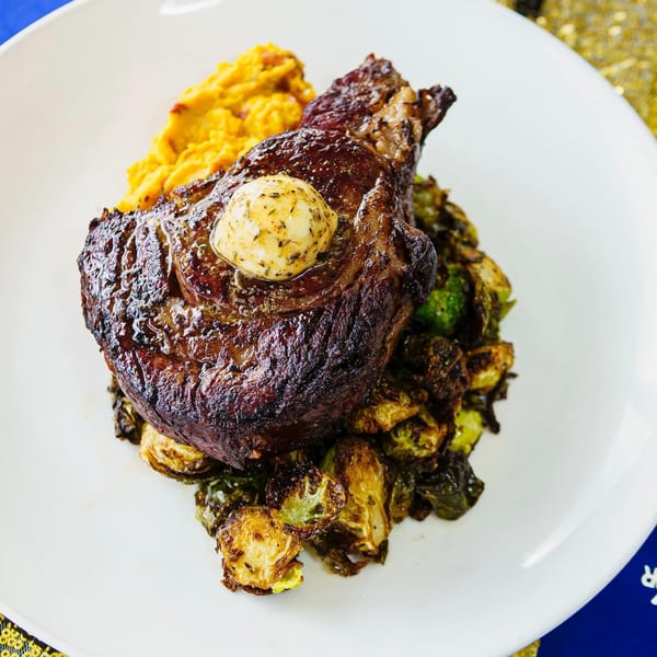 Seared steak with a pat of herb butter, roasted Brussels sprouts, and mashed sweet potatoes.
