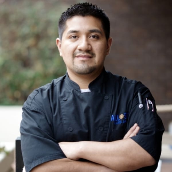 Chef Luis Jara of All Set Restaurant & Bar, wearing a black chef's coat with arms crossed.