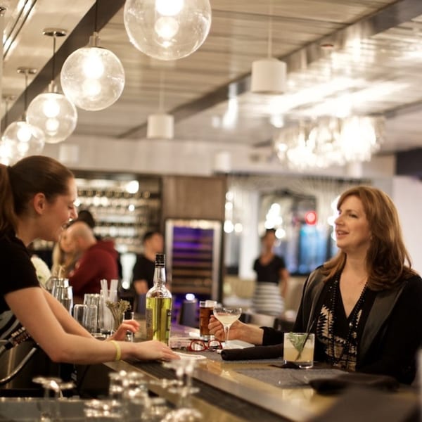 A bartender serves a female customer a cocktail at the All Set Restaurant & Bar.
