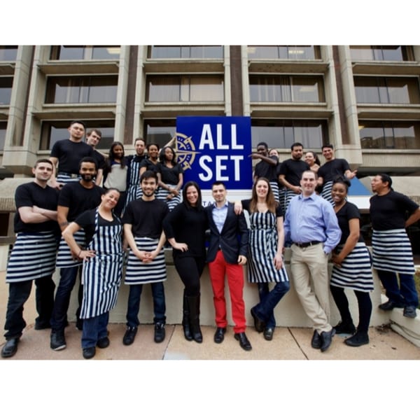 All Set Restaurant & Bar staff, a diverse group, pose in front of the restaurant's sign.