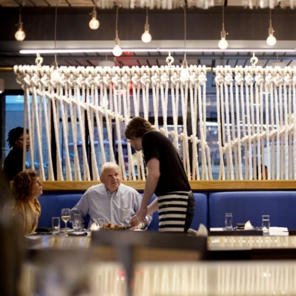 A server attends to guests seated at a blue booth in All Set Restaurant & Bar.