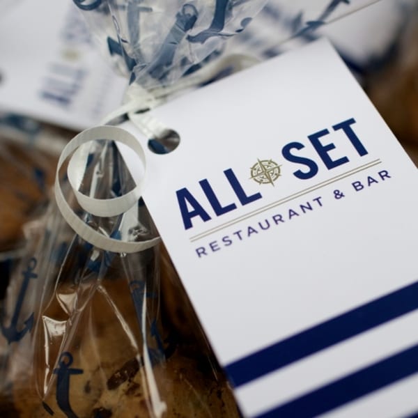 All Set Restaurant & Bar branded tag on a clear bag with anchor patterns and treats.