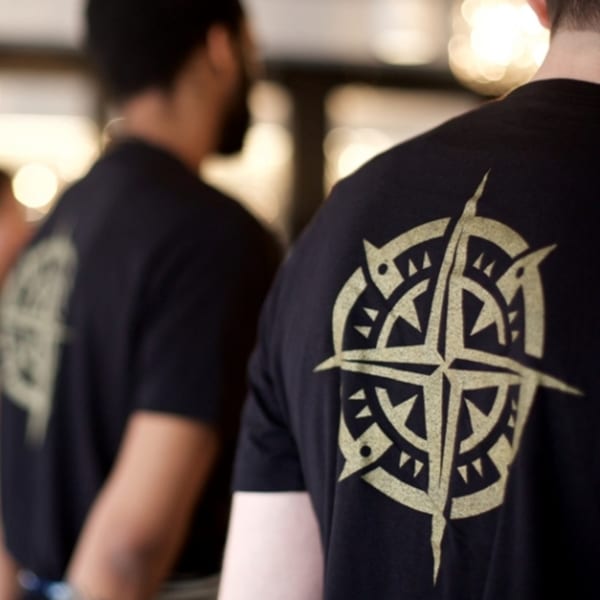 Two All Set Restaurant & Bar staff members wearing black t-shirts with a compass rose logo.
