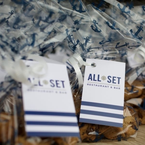 All Set Restaurant & Bar branded gift bags with anchor patterns and white ribbon ties.