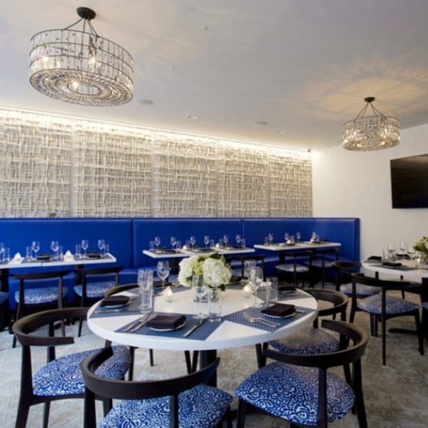 All Set Restaurant & Bar dining room with blue booths, round tables, and crystal chandeliers.